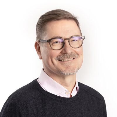 Hymyilevä silmälasipäinen mies.