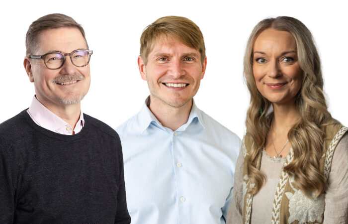 Kaksi miestä ja yksi nainen hymyilevät rivissä.
