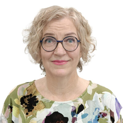 Silmälasipäinen nainen katsoo kohti.