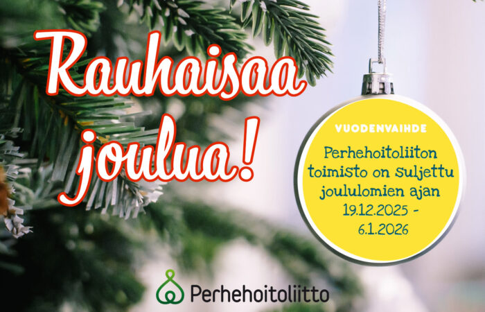 Muovisen joulukuusen oksalta roikkuu keltainen pallokoriste.