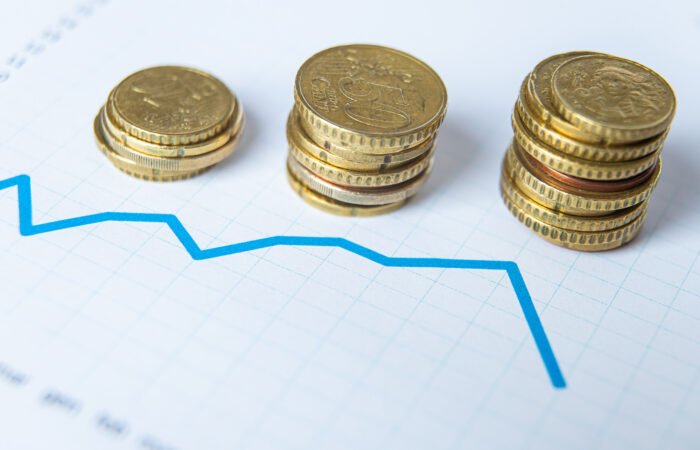 Kolme kolikkopinoa paperin päällä. Paperissa näkyy tilastokäyrä.