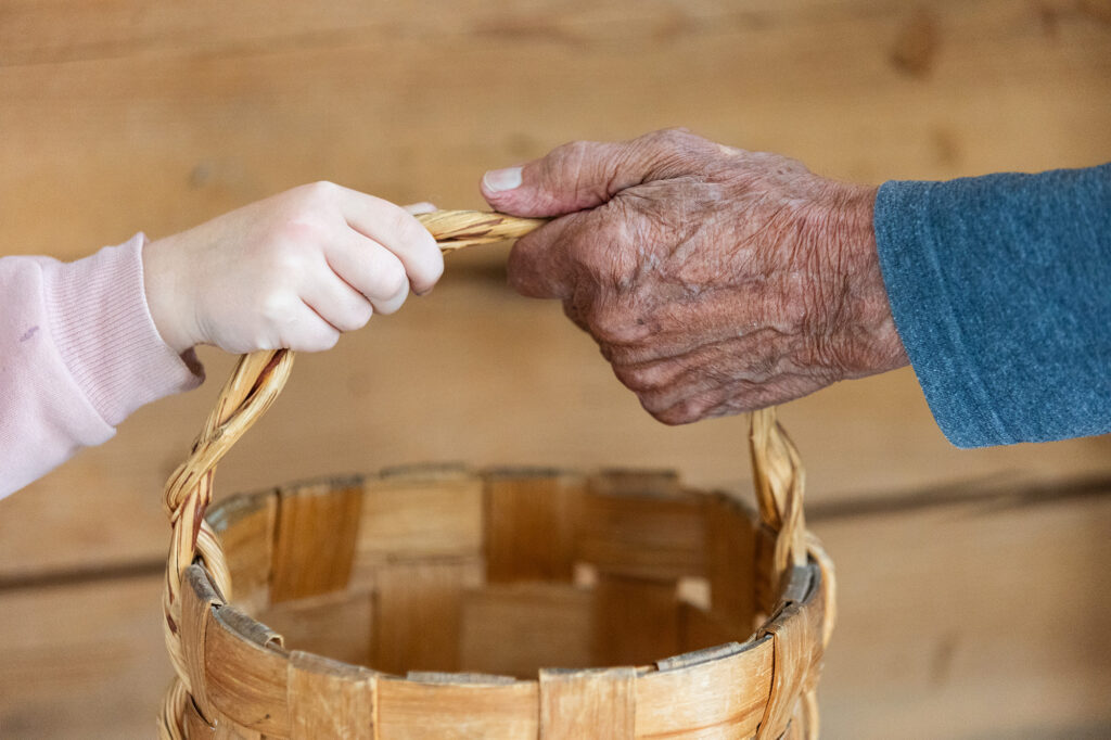 Lapsi ja ikäihminen pitävät kiinni tuohikorin kahvasta.