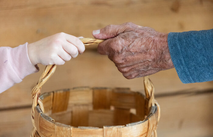 Lapsi ja ikäihminen pitävät kiinni tuohikorin kahvasta.
