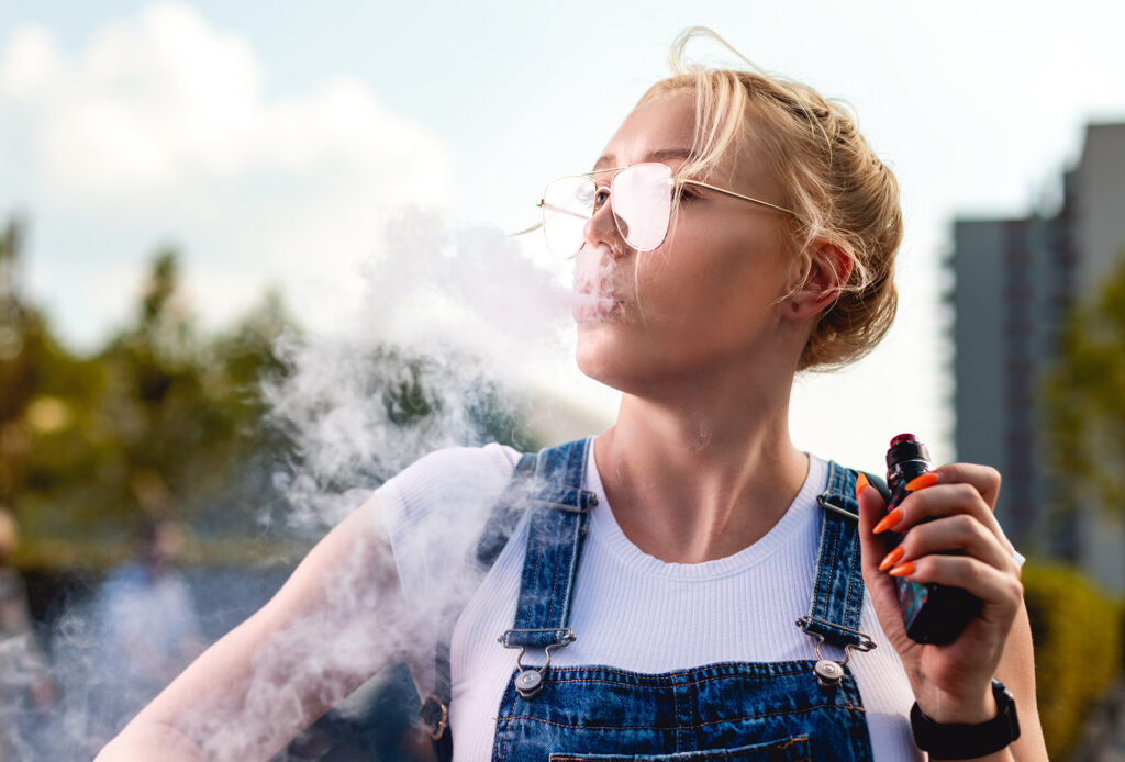 Nuori nainen vapettaa eli polttaa sähkötupakkaa.