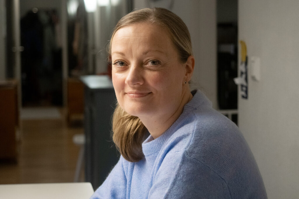 Hymyilevä nainen, jolla on sininen paita.