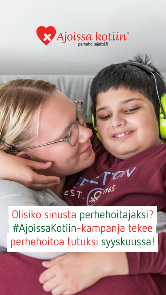Silmälasipäinen aikuinen ja lapsi, jolla on kuulosuojaimet, halaavat.