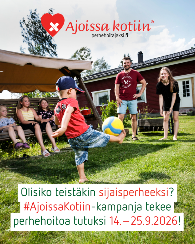 Pieni poika potkaisee palloa omakotitalon pihanurmikolla muun perheen katsellessa vieressä.
