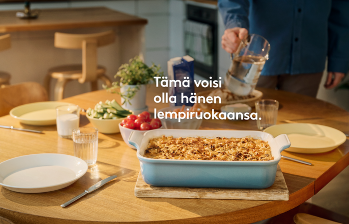 Ruokapöydällä laatikkoruokaa, lautasia, vihanneksia ja vesikannu.