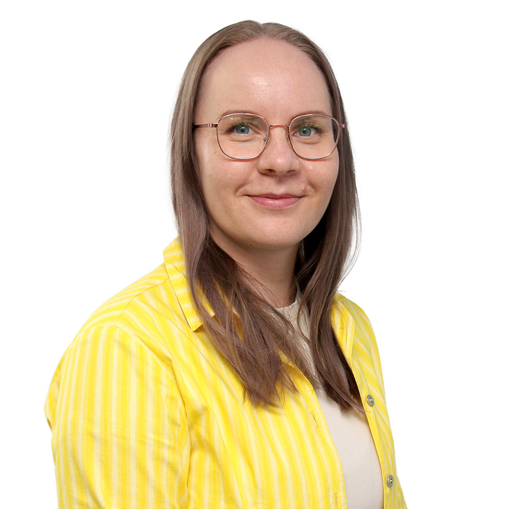 Keltapaitainen nainen hymyilee.