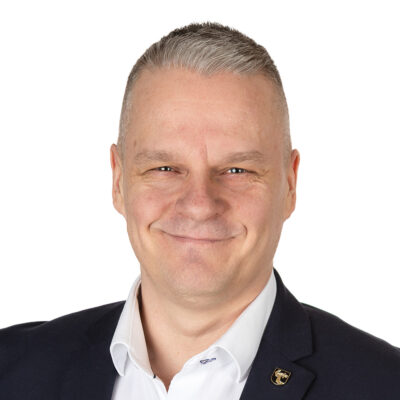 Valkokauluksinen mies hymyilee.